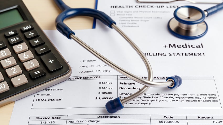 Stethoscope and calculator on top of medical bill