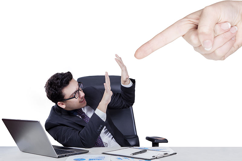 Giant hand pointing at a guilty office worker