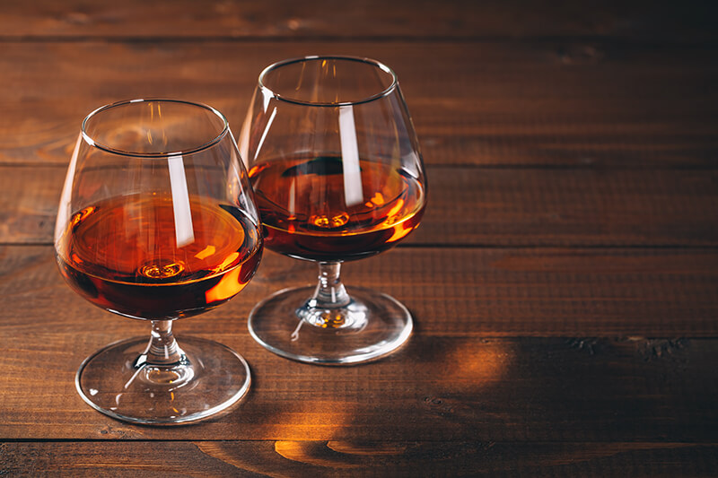 two glasses of cognac on a wooden table