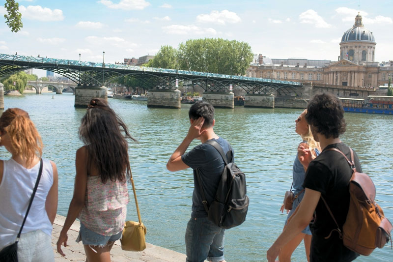 Young travelers walk along the Seine River in Paris