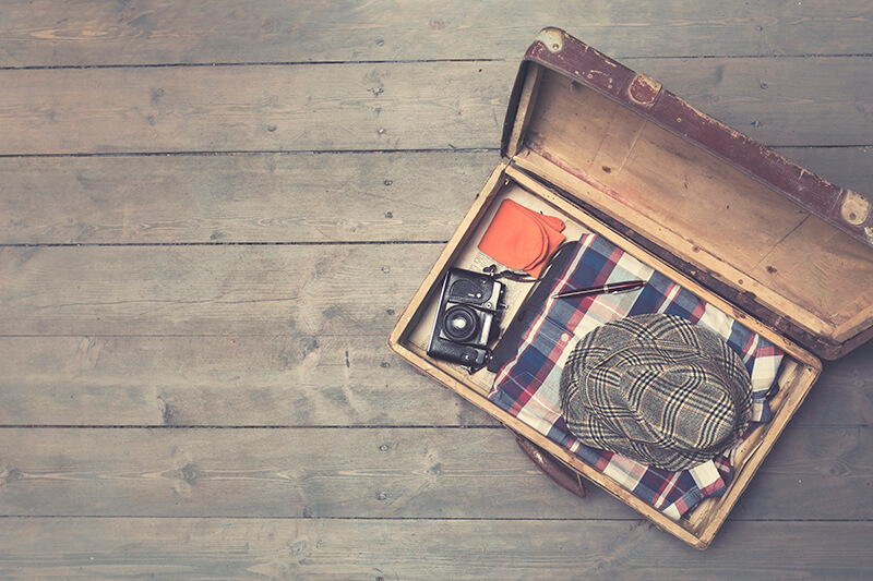 opened vintage suitcase with clothes and camera