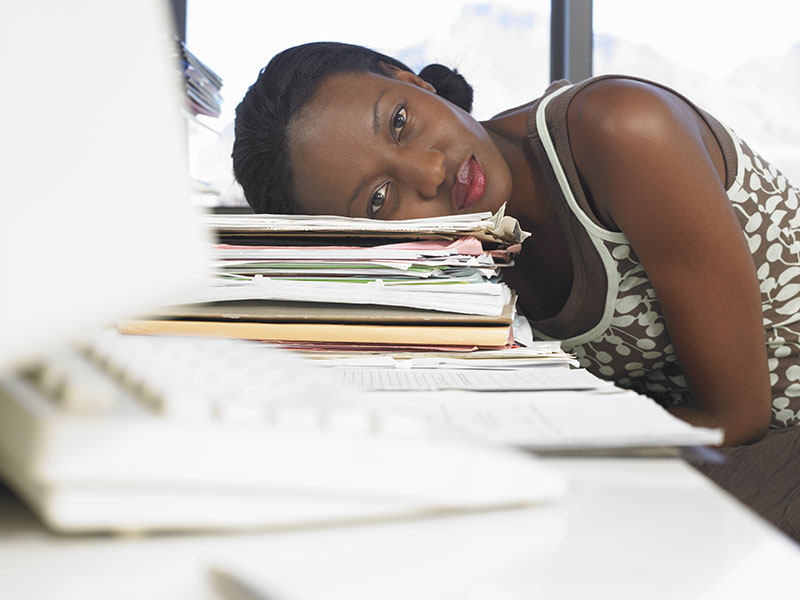 Woman leaning on desk piled with papers