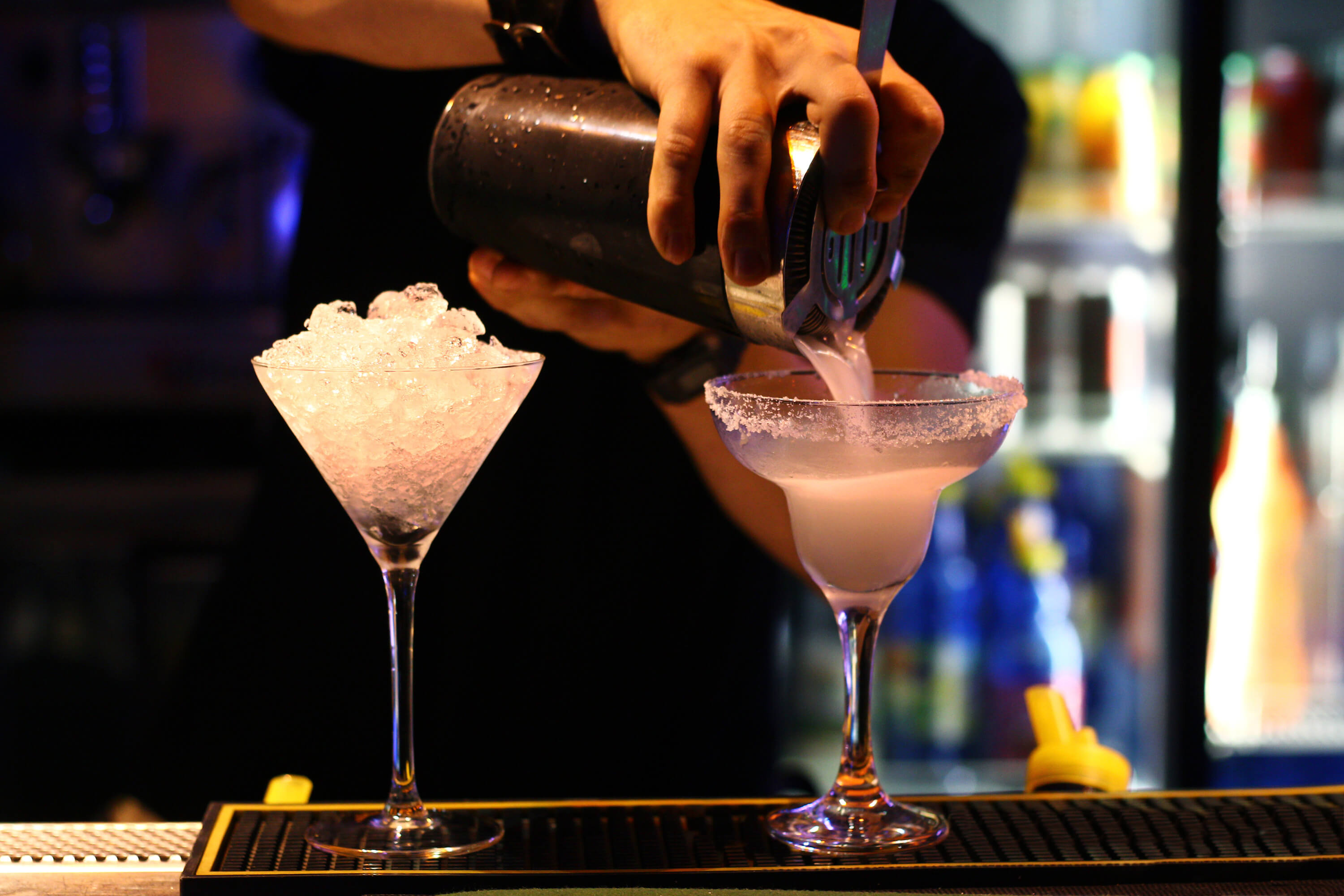 Bartender straining cocktails from cocktail shaker