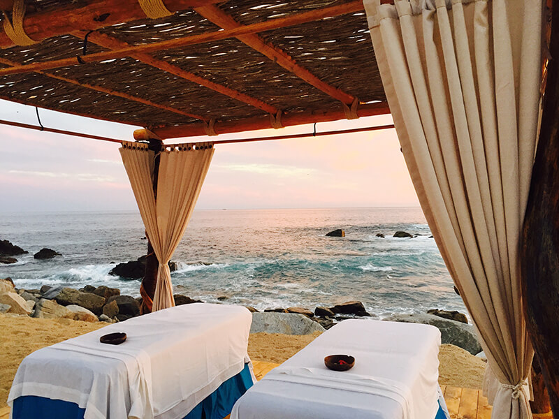 A spa cabana on the beach with two massage tables