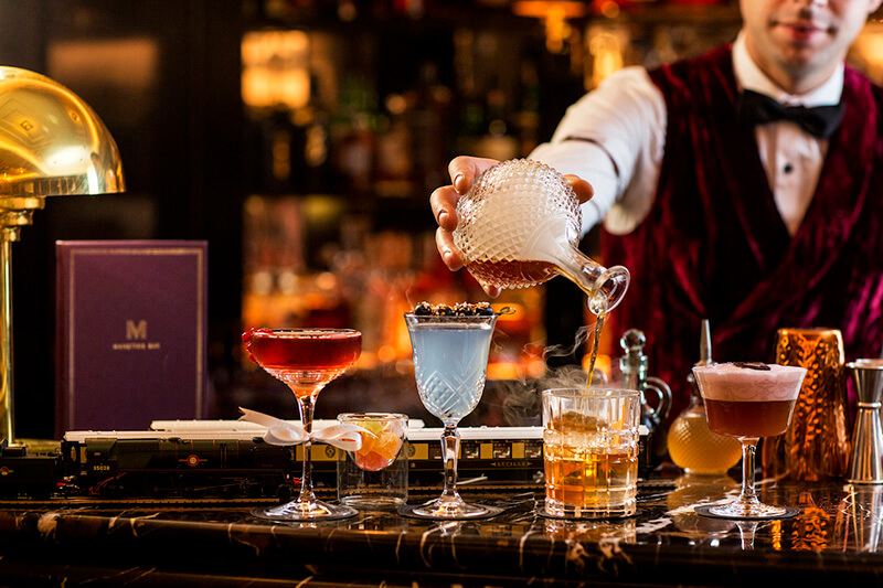 four cocktails being poured by a mixologist