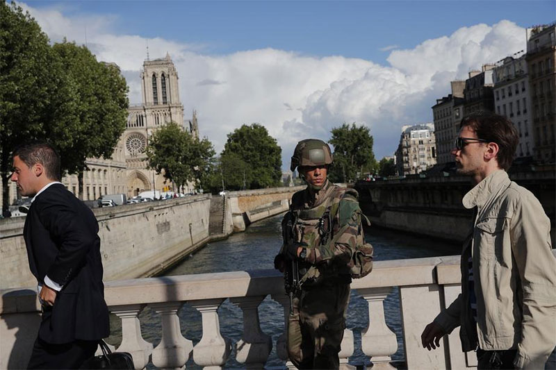 A soldier patrols on a bridge after a man attacked officers with a hammer outside Notre Dame cathedral seen in the backgroun