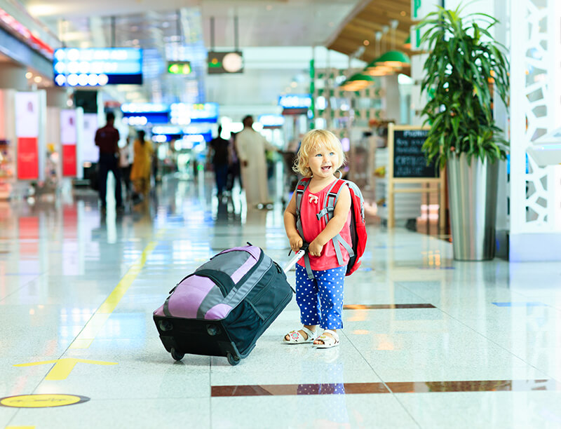 smiling toddler with luggage at an airport