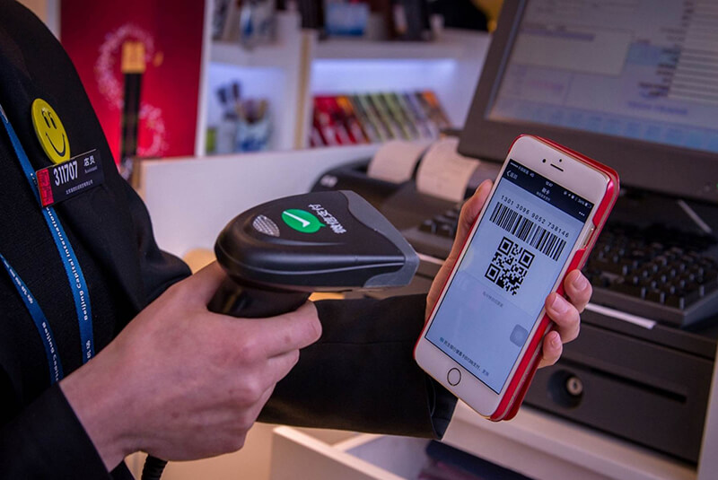 woman scanning a smartphone QR code to pay for item