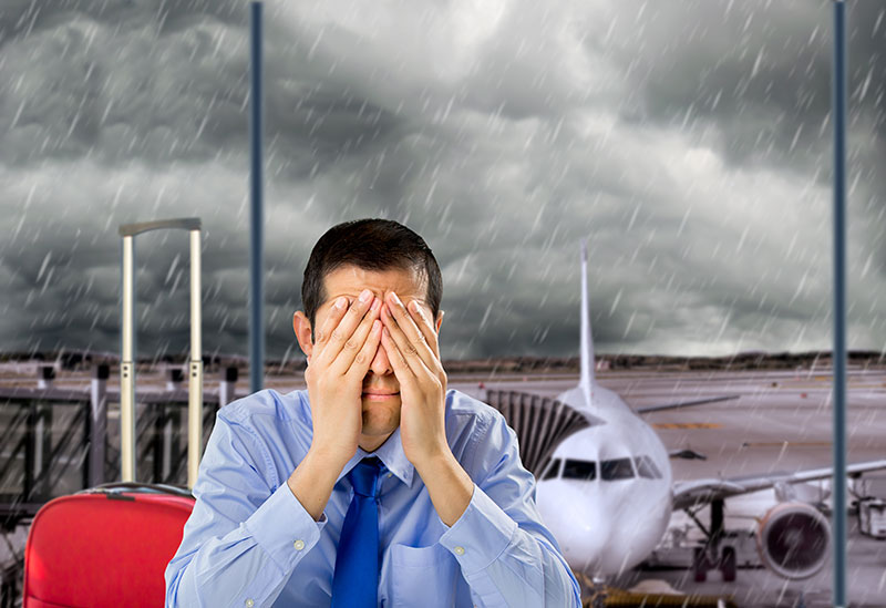 Businessman crying in airport with stormy weather in the background