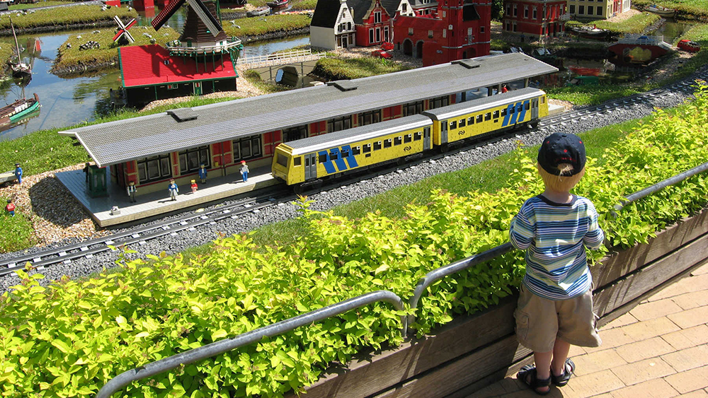 A little boy looking at a Lego train