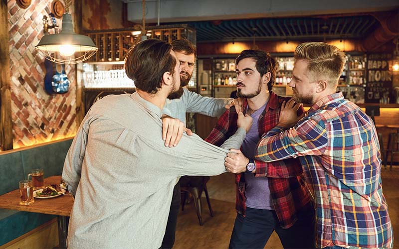A group of male patrons attempt to fight in a bar