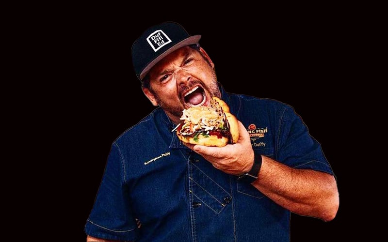 Chef Brian Duffy takes a big bite of a giant sandwich 