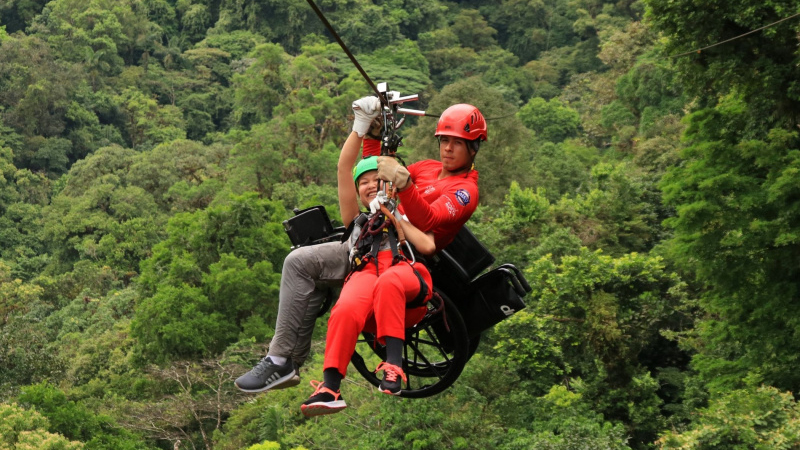 Man zip lining with a child in a wheelchair in Costa Rica