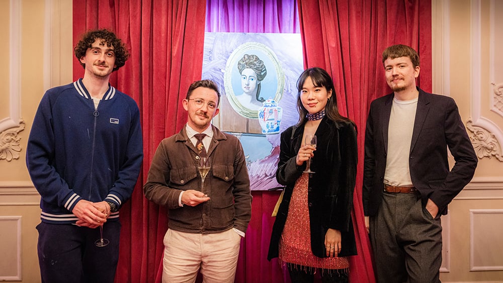Artists standing in front of a painting of Queen Anne