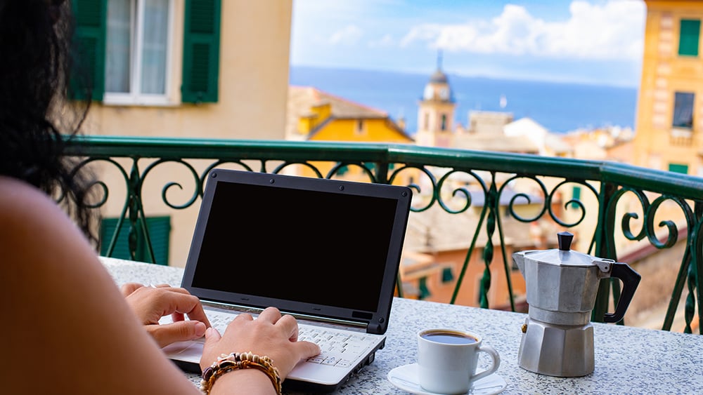 Woman working on laptop on patio in Europe with espresso