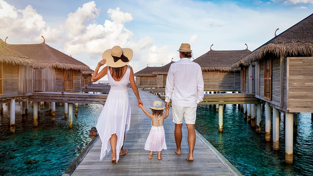 family on vacation with overwater bungalows in background