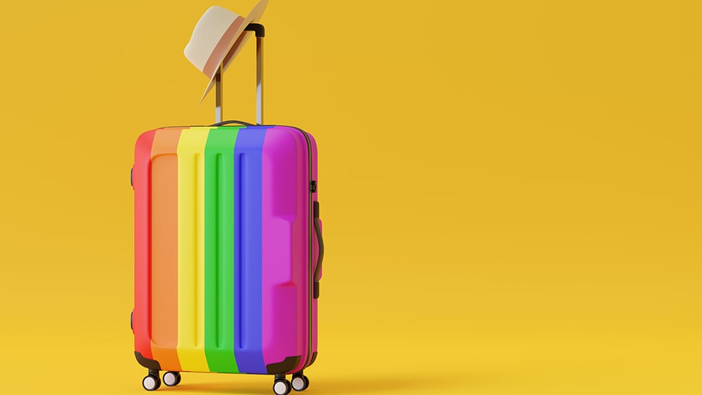 A Pride flag-colored suitcase on a yellow background
