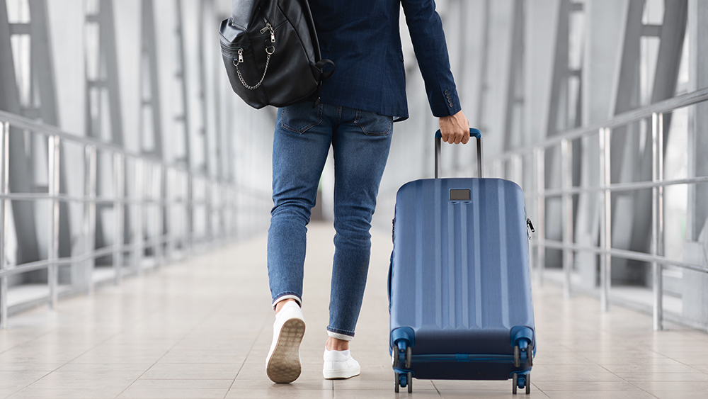 man in airport with suitcase and backpack