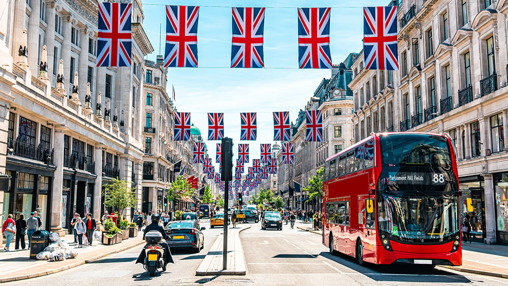 London with Union Jack flags hanging across and street and a red bus