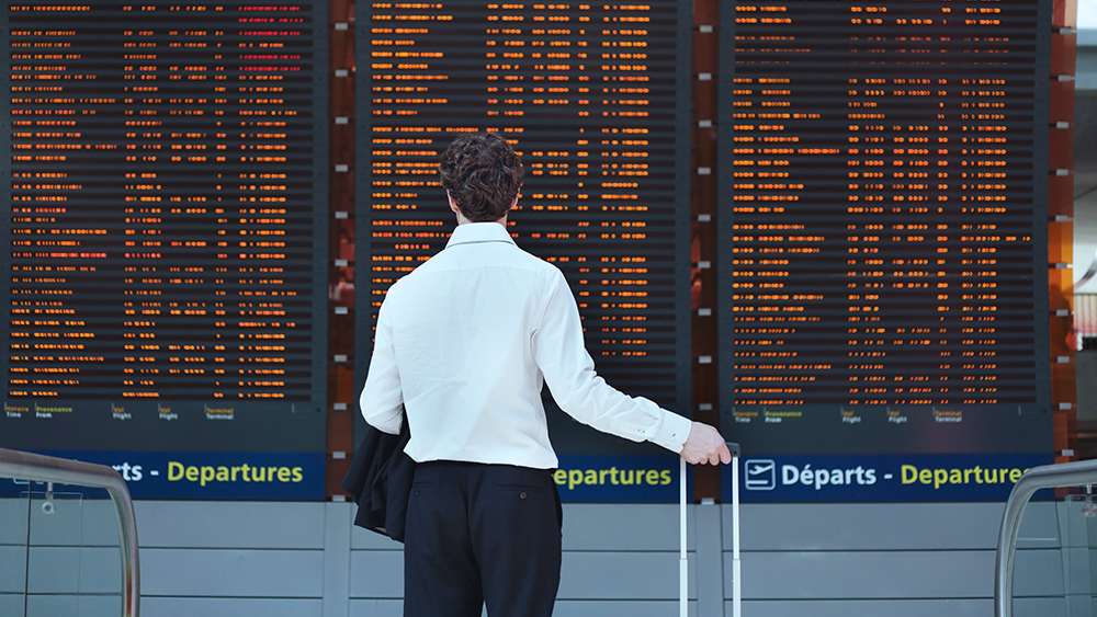 man looking at timetable board at airport