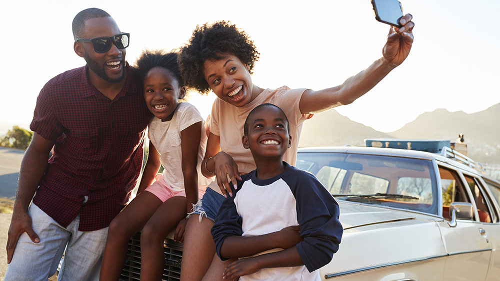 family taking selfie on car hood