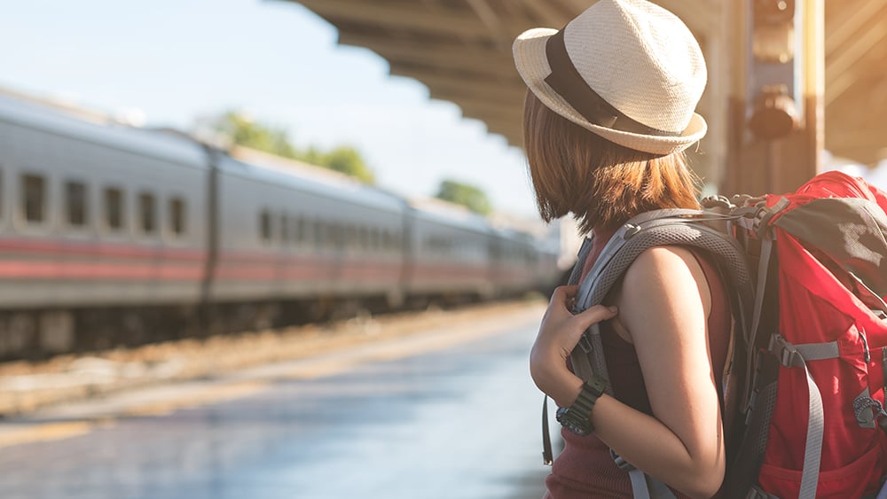 Woman with a red backpack waiting for a train