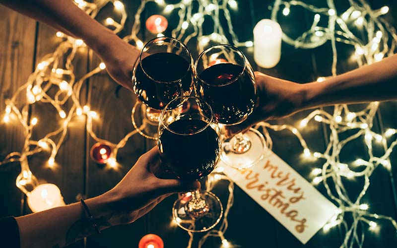 Friends toast with glasses of red wine during the holiday season