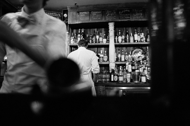 Two waiters work at a busy bar shot in black and white