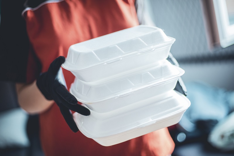 A woman holds several takeout containers in her hands