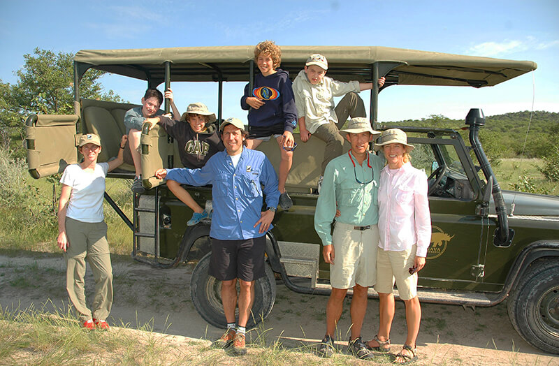 Family on safari standing in front of a 4x4 SUV