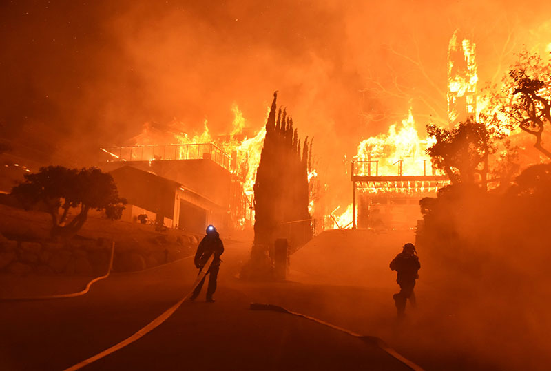 Firefighters work to put out a blaze burning homes in Ventura California 