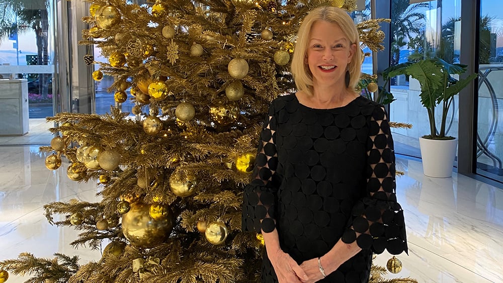 A blonde woman standing in front of a Christmas tree