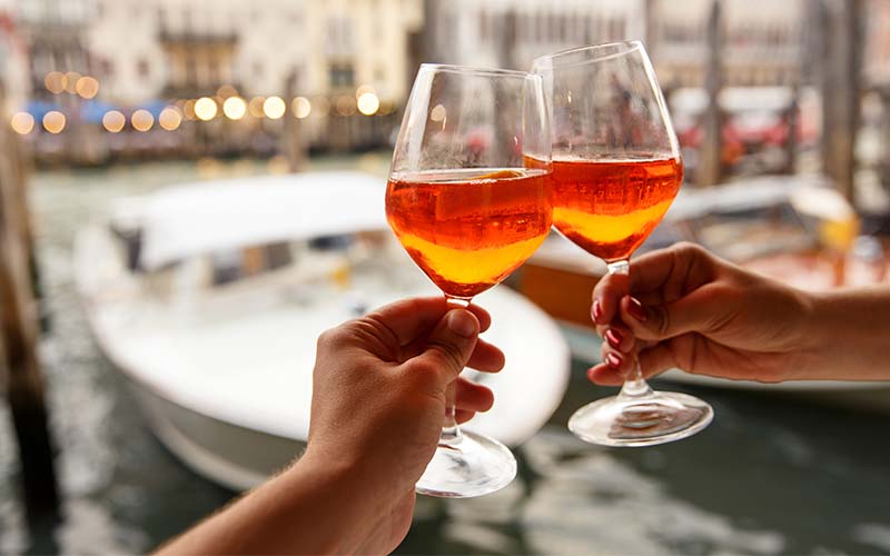 Two people toast with dazzling glasses of orange wine