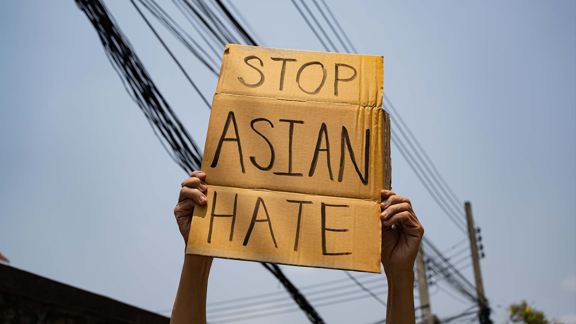 A hand holds a sign saying End Asian Hate