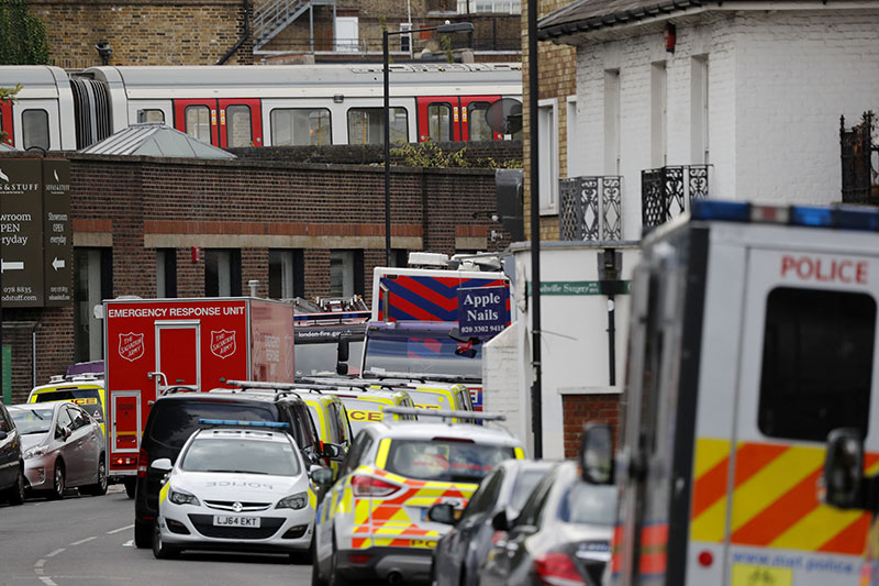 The train on which a homemade bomb exploded stands above parked police vehicles on a road below at Parsons Green subway sta