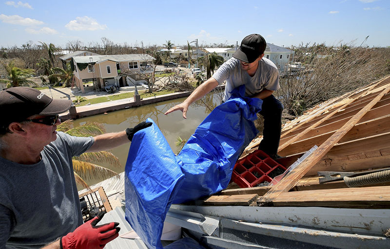 Bob Fiorile 72 and Todd Brown 42 right pull a tarp onto the exposed roof of Fioriles home in Big Pine Key 