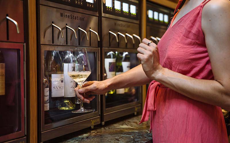 A woman pulls a glass of wine from the wine wall at MPourium in Greenville NC