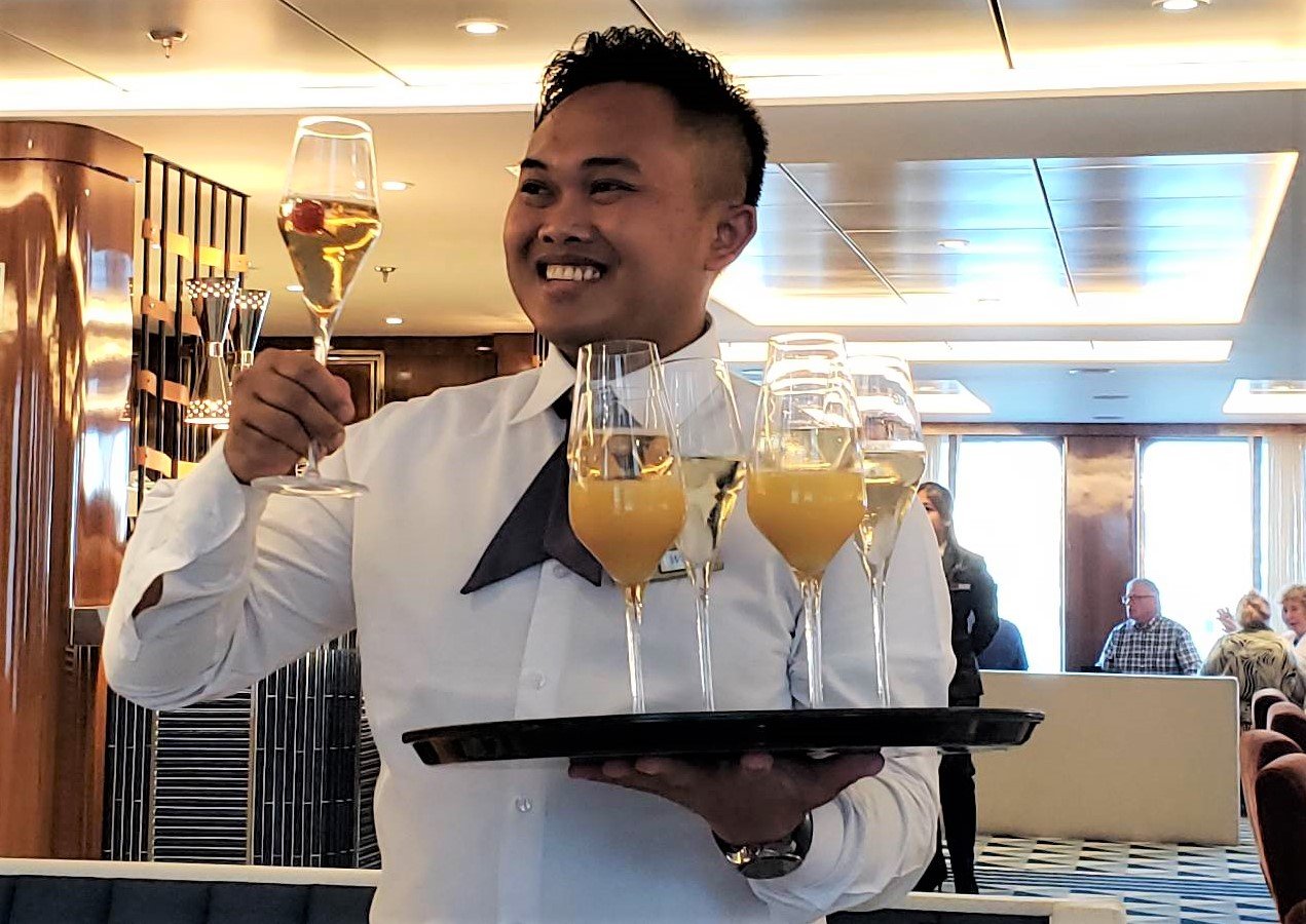 Server offers complimentary drinks to guests at the Captains Welcome Party on Atlas Ocean Voyages World Traveller