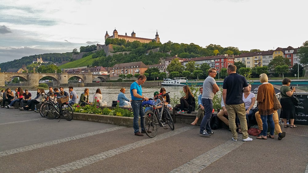 People standing along a promenade adjacent to the Main River