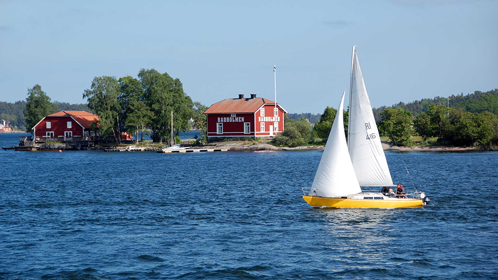 A sailboat zips by one of the tiny granite islands in Stockholms archipelago