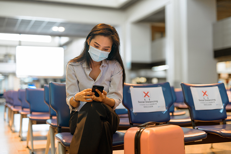 Woman at airport with mask and luggage