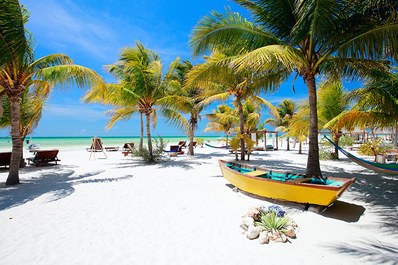 Beach beds and hammocks among palm trees at perfect tropical coast on Holbox island in Mexico