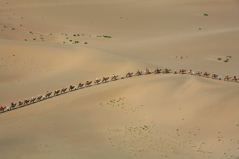 A caravan of tourists on the Singing Sand Dunes of Dunhuang Gansu Province China