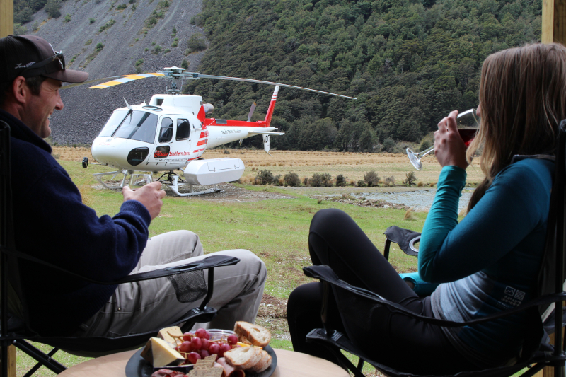 Two people drink wine with a helicopter in the background