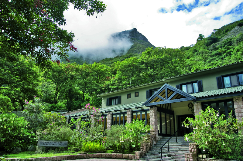 The front of Belmond Sanctuary Lodge with a cloudy mountain in the background