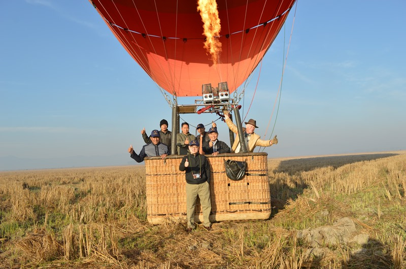 Image of passengers on hot air balloon posing for picture 