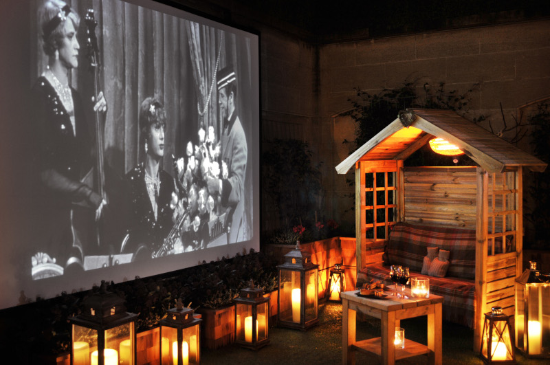 Image of black and white projection with candles scattered about 