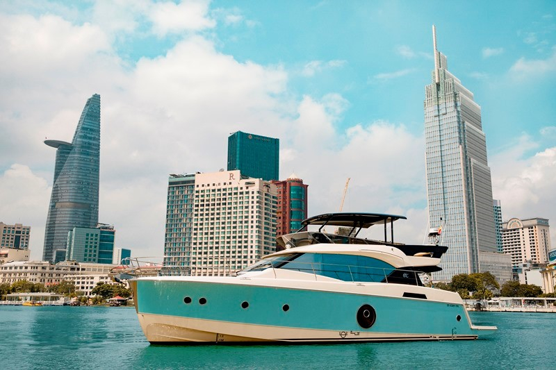 A yacht on the water with city buildings behind it