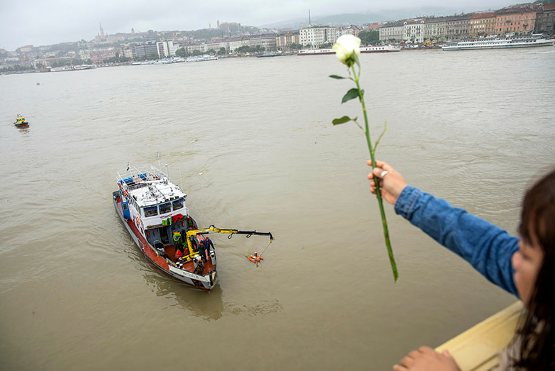 A woman throws a flower from the Margaret Bridge during a search operation on the River Danube in Budapest Hungary