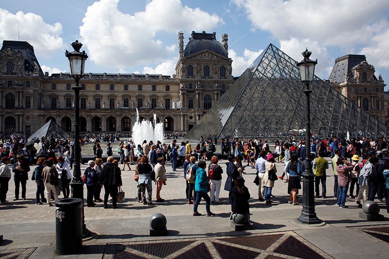 Tourists wait in line to visit the Louvre museum as it reopens 